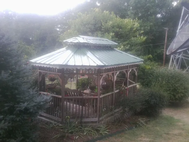Green metal roof on a backyard gazebo surrounded by garden beds in Perry